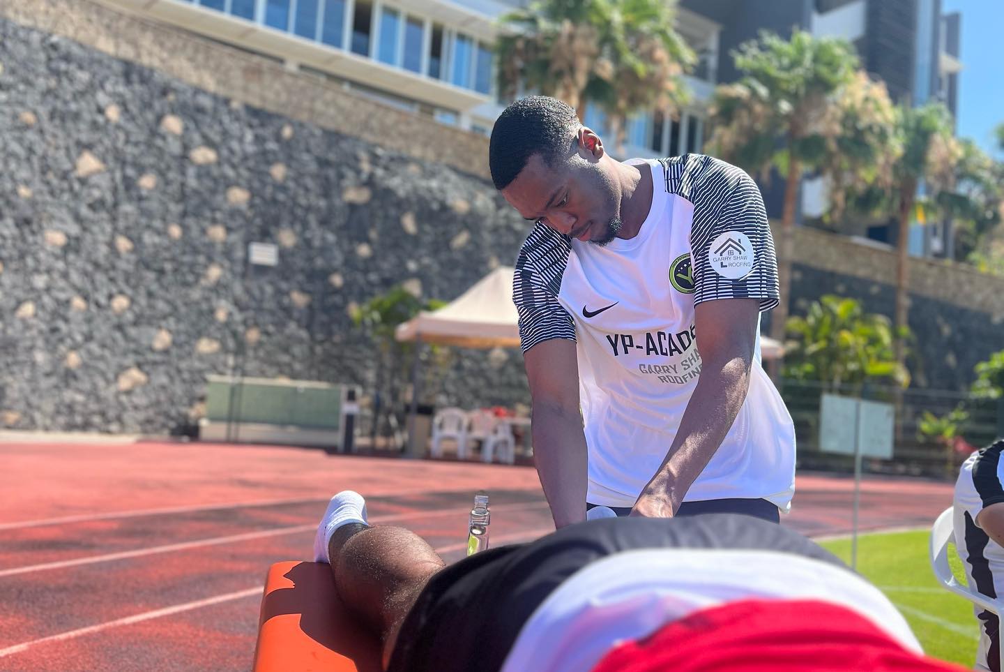 Dom treating an athlete lying at the edge of the running track